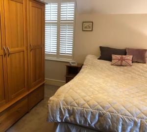 a bedroom with a bed and a wooden cabinet at Victorian cottage in Windsor in Windsor