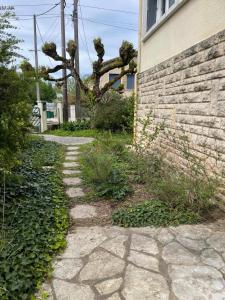 a stone path next to a building with a tree at Bergerac- Grande maison familiale, terrasse, jardin in Bergerac