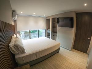 una camera da letto con un letto grande e una televisione di Santorini Apartamentos Amoblados a Pereira Altre 60 foto