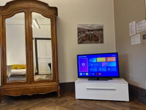 a television sitting on a dresser next to a mirror at Grande chambre élégante Les Chambres Bannacker 25 m2 Centre à pied in Wissembourg