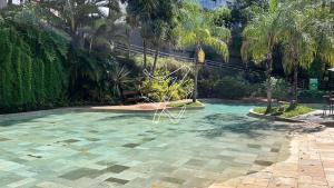ein Swimmingpool in einem Garten mit Palmen in der Unterkunft Luupi - TURISMO in Rio Quente