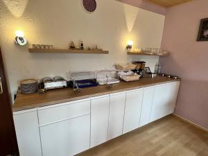 a kitchen counter with white cabinets and plates on it at Pension Döser Strand in Cuxhaven +10 photos