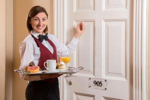 a woman holding a tray of food and orange juice at The Inn at the Spanish Steps Luxury Collection - The Inn at the Spanish Steps in Rome