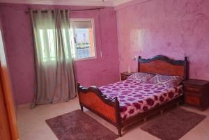 a bedroom with a bed with purple walls and a window at Billa appart in Midelt