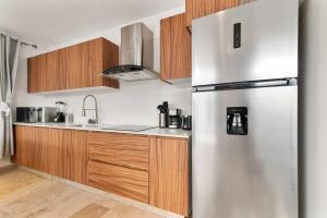 a stainless steel refrigerator in a kitchen with wooden cabinets at Aldea Zama Luxury 2-BR Apt with Pool & Gym in Tulum