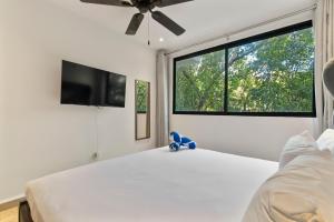 a bedroom with a white bed and a large window at Aldea Zama 2-BR Lux Building Amenities in Tulum +24 photos