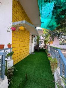 a backyard with a yellow wall and green grass at Its Home - Stay in Aurangabad