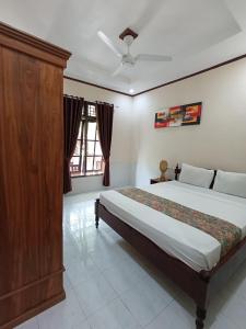 a bedroom with a large bed with a wooden cabinet at Gili Mesari Cottages & Homestay in Gili Trawangan