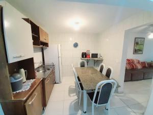 a kitchen with a table and chairs in a room at Casa em condomínio, com piscina, parquinho infantil, internet 500mb, ideal para família, garagem para 2 carros, com 2 quartos sendo 1 suíte, com Smart TV, 400m da PRAIA in Matinhos