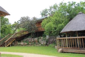 a building with stairs and a grass roof at Emlanjeni Guest Lodge in White River