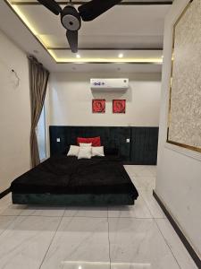 a bedroom with a black bed and a ceiling fan at S H Residence & APARTMENTS in Mūsapur