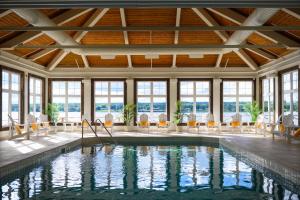 una piscina in una stanza con sedie e un soffitto con finestre di Rodd Miramichi a Miramichi