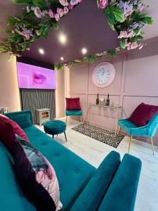a living room with a blue couch and a clock at The Ultimate Hen Suite with Bar & Makeup Room in Manchester