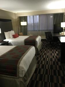 a hotel room with two beds and a desk at Ramada Plaza by Wyndham Charlotte South End Airport in Charlotte