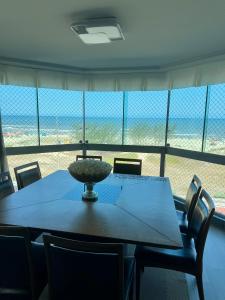 a dining room table with a view of the beach at Apartamento a beira mar in Capão da Canoa