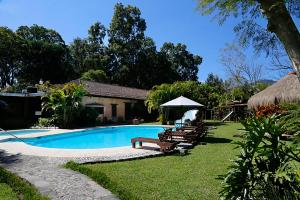 a swimming pool with benches and a house at Hotel Real Plaza in Antigua Guatemala