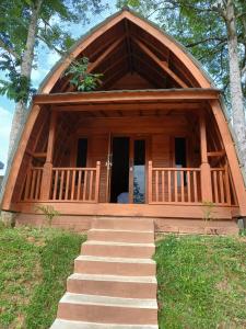 a log home with a staircase leading to a porch at Naraya Nusantara Resort & Kafe in Sepaku