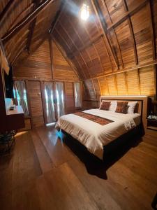 a bedroom with a large bed in a wooden room at Naraya Nusantara Resort & Kafe in Sepaku