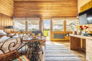 a room with a dining table and a kitchen with wooden walls at The Cricket Pavilion in Warham