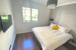 a white bed in a room with a window at Renovated 2 bedrooms - Boulevard de la Croisette in Cannes +5 photos