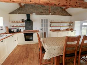 a kitchen with white cabinets and a table with chairs at Fferm Porthdafarch South Farm House in Holyhead