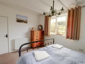 a bedroom with a bed and a dresser and a window at Fferm Porthdafarch South Farm House in Holyhead
