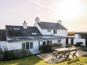 a white house with a picnic table in front of it at Fferm Porthdafarch South Farm House in Holyhead