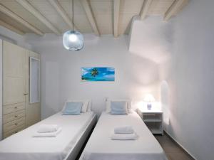 two beds in a room with white walls at The Mykonian Sunset Villas - 10min from Town in Agios Ioannis Mykonos +75 photos