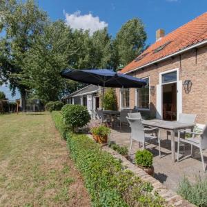un patio con tavolo, sedie e ombrellone di Groepswoning in hart van Zeeland 8 personen VP051 a Oudelande