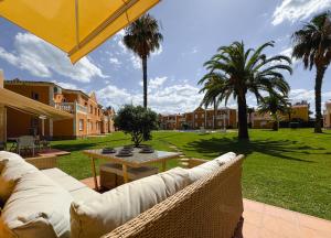 eine Terrasse mit einem Sofa, einem Tisch und Palmen in der Unterkunft Coraline by Midelisa in Oliva