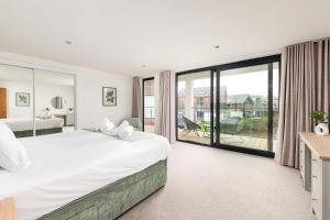 a bedroom with a large bed and a balcony at Minety Lake 64 ML64 Lower Mill Estate Cotswolds in Somerford Keynes +39 photos