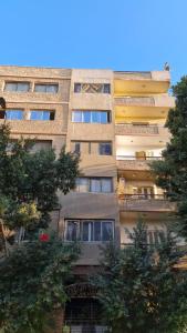 a tall building with trees in front of it at Pyramids Heritage suites in Ghaţāţī