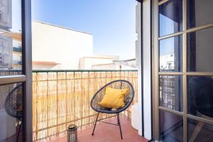 a wicker chair with a yellow pillow sitting on a balcony at Nordik Rooms Village - Torremolinos "Undredal" in Torremolinos