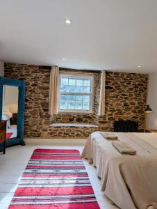 a bedroom with a bed and a brick wall at Ramble & Rye - The Nest in Talland +12 photos