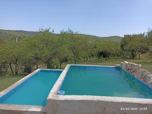 a blue swimming pool with trees in the background at vistas del valle casa amarilla in Valle Hermoso