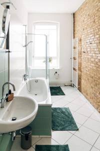 baño con lavabo, bañera y alfombras verdes en lauschig living, en Flensburg