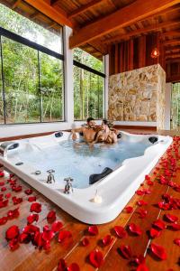 two people sitting in a bath tub with roses on the floor at Vila Europeia Hotel in Serra Negra