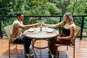 a man and woman sitting at a table with wine glasses at Vila Europeia Hotel in Serra Negra