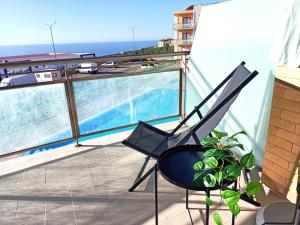 a chair on a balcony with a view of the ocean at Like-Home-T1-Sun & Beach-Pools, AC in Ericeira