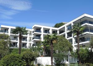 an apartment building with palm trees in front of it at Fiore Rosa by Fewotessin in Ascona