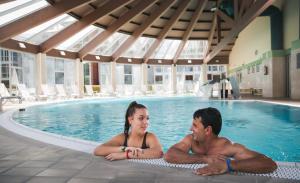 a man and a woman laying in a swimming pool at Lobios Caldaria Hotel Balneario in Bubaces