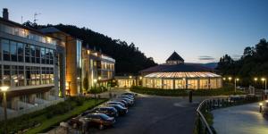 a row of cars parked in a parking lot next to a building at Lobios Caldaria Hotel Balneario in Bubaces