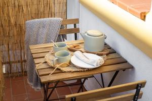 a wooden table with cups and plates on a balcony at Nordik Rooms Village - Torremolinos "Undredal" in Torremolinos