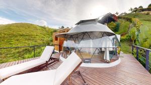 a glass house on a wooden deck with two chairs at Bliss Sanctuary Vista - Glamping and Club in Guatapé