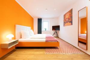 a bedroom with orange walls and a bed and a mirror at Bunter Hund Apartments - Hund, Parkplatz, Wintergarten in Rothenburg ob der Tauber