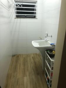 a white bathroom with a sink and a window at Recanto do Peró in Cabo Frio