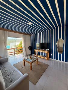 een woonkamer met een blauwe en witte streepmuur bij Suíte Atenas com hidro aquecida - Arraial do Cabo in Arraial do Cabo