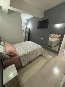 una piccola camera da letto con un letto e uno specchio di Casa no Perequê a 300 metros da praia - Espaço inteiro a Ilhabela