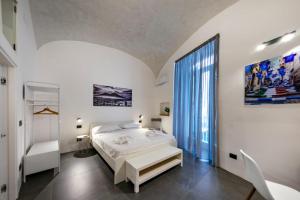 a white bedroom with a bed and a large window at Casa Mirelli By Dimorra in Naples