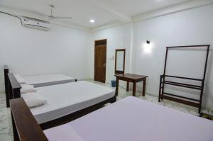 a room with three beds and a table in it at Hotel Sanhida Polonnaruwa in Polonnaruwa